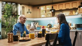 Elderly couple enjoys natural morning routine with healthy homemade breakfast, eating pastry and drinking coffee. Husband and wife shares casual conversation for candid moment. Camera A. - Powered by Shutterstock - Get 15% off with code: PIKWIZARD15