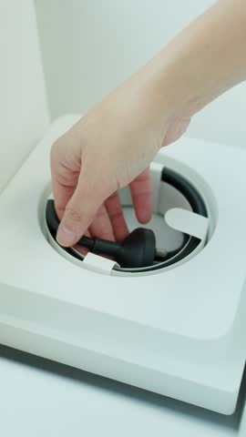 Hands carefully unbox and extract power cable from minimalist desktop computer packaging in bright light