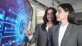 Two people are discussing cybersecurity in an office. They interact with a digital screen showing data and security graphics. The focus is on collaboration and technology use. - Powered by Shutterstock - Get 15% off with code: PIKWIZARD15