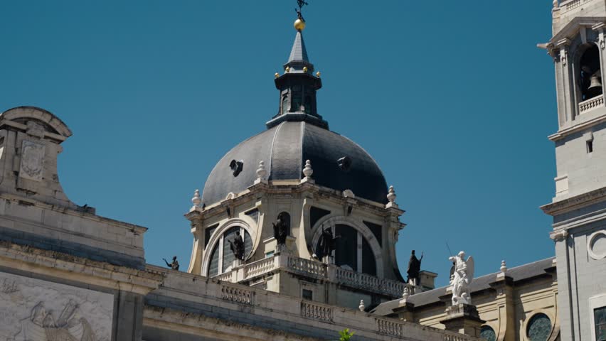 The dome of Almudena Cathedral in Madrid Spain rises against a bright clear blue sky.