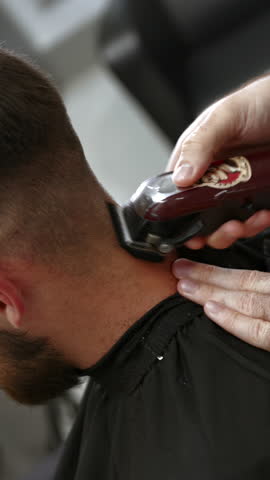 Professional barber using electric clipper on client