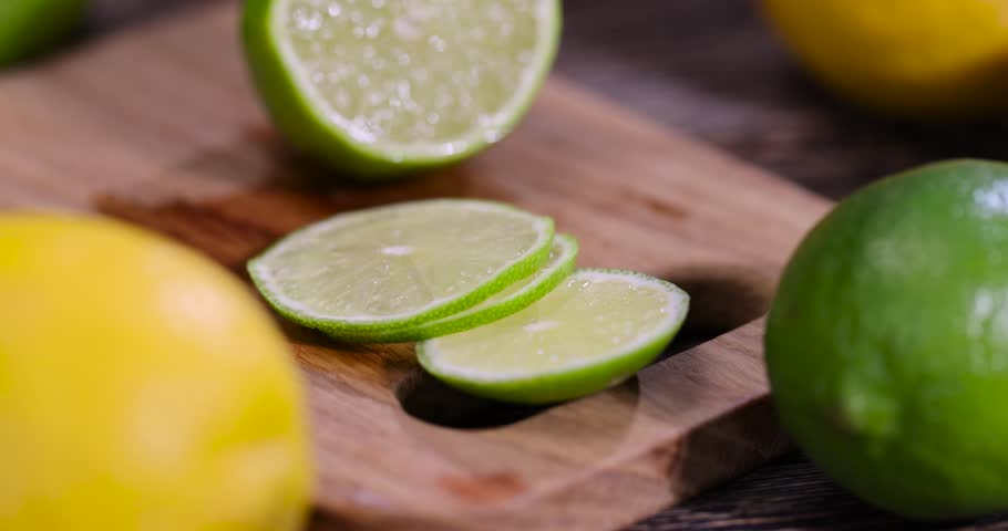 sliced juicy sour lime lying on the table with yellow lemons , sliced ripe citrus fruits lime and large lemons are lying on a wooden table