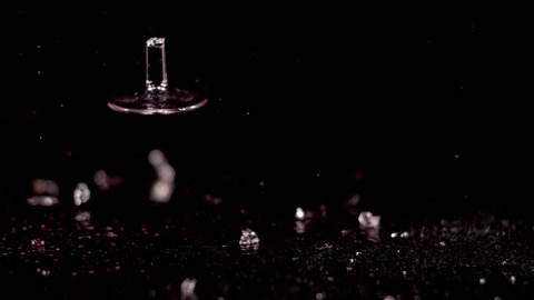 A  glass of red wine falls in slow motion against a black background. It shatters as it hits the ground, spilling its contents and sending shards of glass flying everywhere.