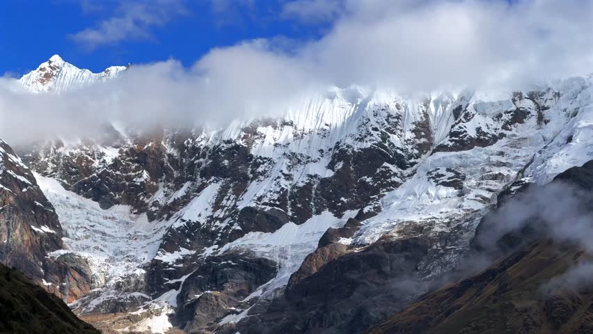 Mount Humantay Peruvian Andes snow capped glacier mountain Salcantay Inca trail trek Peru aerial drone pan left motion low fog clouds blue sky rainy dry season Laguna Humantay Soray Anta Cusco region