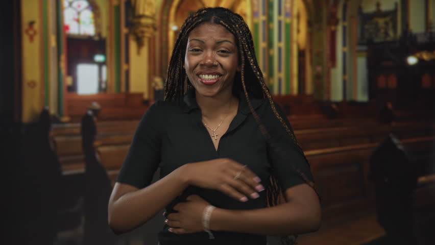 Woman with cross necklace and arms outstretched in church nave, smiling and reaching forward; joy faith welcome.