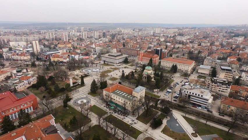 Drone video of Pleven center on March 3, 2019, showing landmarks, the square, the Ossuary, church, municipal building, fountains, and people walking with a long national flag, Pleven, BG,03 March 2019