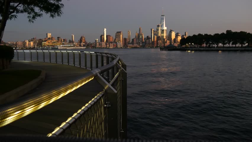 New York City Manhattan Downtown Financial District skyline, World Trade Center tower skyscraper from New Jersey, Hoboken pier, United States. River waterfront urban cityscape, evening dusk twilight.