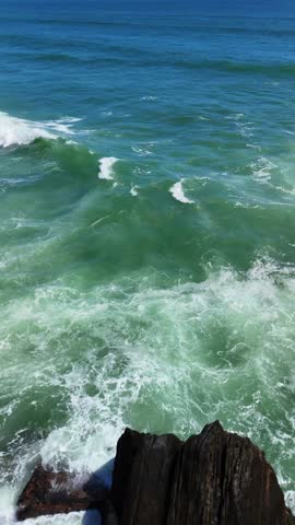 Powerful ocean scene with large waves crashing against dark jagged rocks