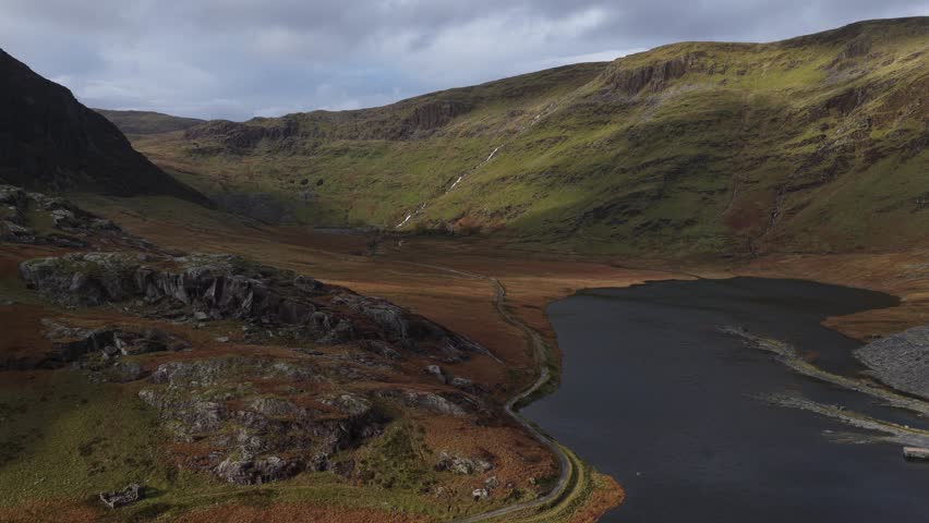 Picturesque view of Llyn Cwmorthin and Moelwyn Mawr in the Moelwynion range of Eryri National Park, showcasing a tranquil lake nestled within a dramatic landscape with historic slate mining ruins.