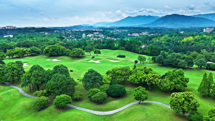 Aerial shot of the beautiful golf course and green forest with mountain natural landscape in summer