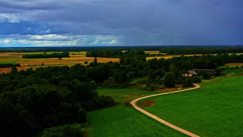 Winding countryside path under dramatic storm clouds in summer rural farmland