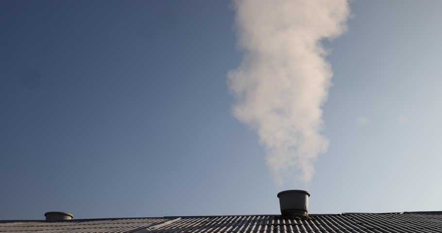 white smoke coming from a wide pipe against a sky background, white steam coming from a pipe during heating of a large industrial premises in cold weather