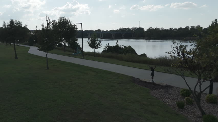 Drone pullback from bikepath along Arkansas River to front lawn of museum oil pump jack