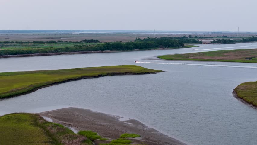 Aerial drone footage shows a winding river carving through green marshes and grassy islands in South Carolina