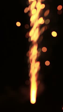 Sparkler fountain ignites with vibrant sparks, illuminating the dark surroundings, showcasing a dazzling display of light, camera follows upward motion