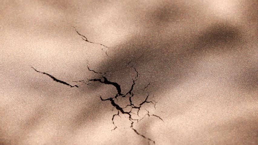 Dynamic macro video of a dark central cracking rapidly, forming and spreading into complex veins before slowly dissolving back into shimmering golden surface.