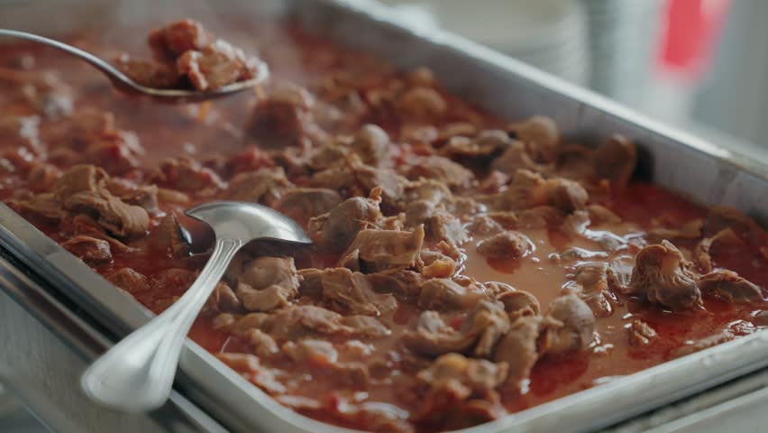 Close view of steaming moelas in tomato sauce at a Portuguese buffet