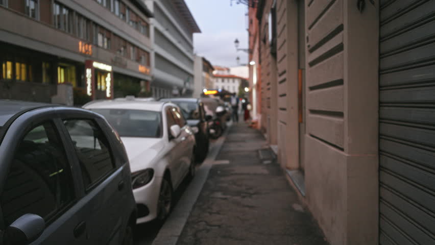 Florence street scene with parked cars, narrow sidewalk and soft defocused bokeh on distant buildings street; background backdrop copyspace.