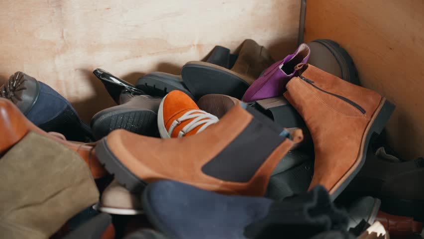 Mixed shoes piled together inside wooden container