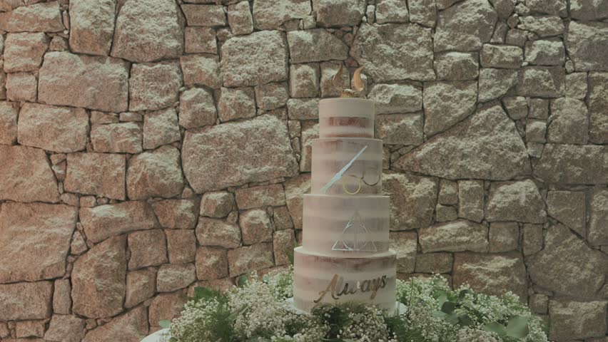 Decorated multi tier wedding cake with flowers before stone wall