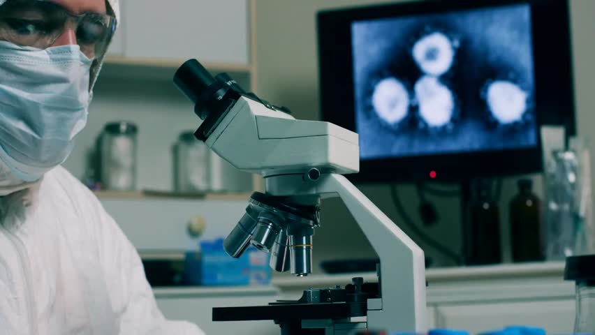 Lab technician places a coronavirus sample under a microscope, highlighting scientific research, virology, and laboratory safety procedures.