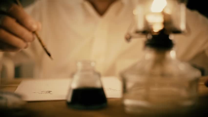 Dolly shot of a man writing with a dip pen on paper, highlighting vintage writing, calligraphy, artistic practice, and historical desk work.