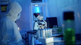 A virologist in protective lab gear carefully mixes two solutions in a beaker, illustrating laboratory research, virus study, and scientific experimentation in 4K. - Powered by Shutterstock - Get 15% off with code: PIKWIZARD15