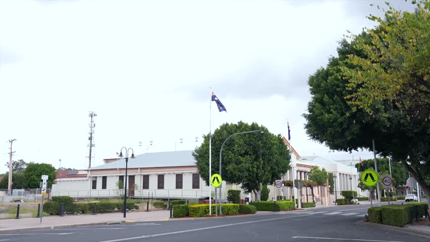 Wide shot of the Moree War Memorial Hall in New South Wales, viewed across the street with the Australian flag flying above the building.