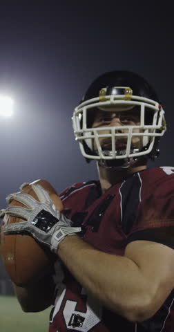 An American football player practicing throwing and catching the ball on a field