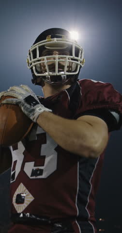 An American football player practicing throwing and catching the ball on a field