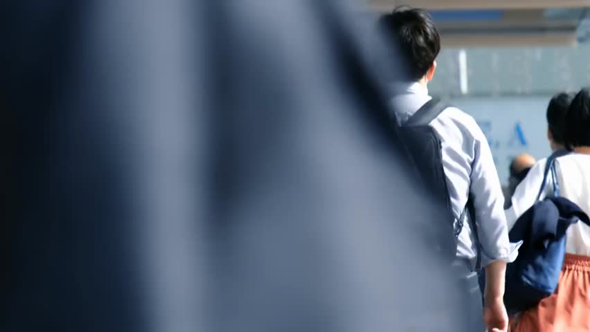 Slow-motion low-angle view of people commuting during the busy morning rush hour, capturing urban movement, daily life, and the energy of a bustling city street.