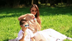 Preschool boy having fun blowing soap bubbles in park. Game of blowing bubbles. Caucasian boy and mother celebratong mothers day together outside. - Powered by Shutterstock - Get 15% off with code: PIKWIZARD15