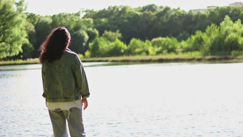 Tender moment of mother hugging her son, both smiling with the glistening lake in the background. Ideal for concepts of love, security, and family affection in scenic environment. High quality