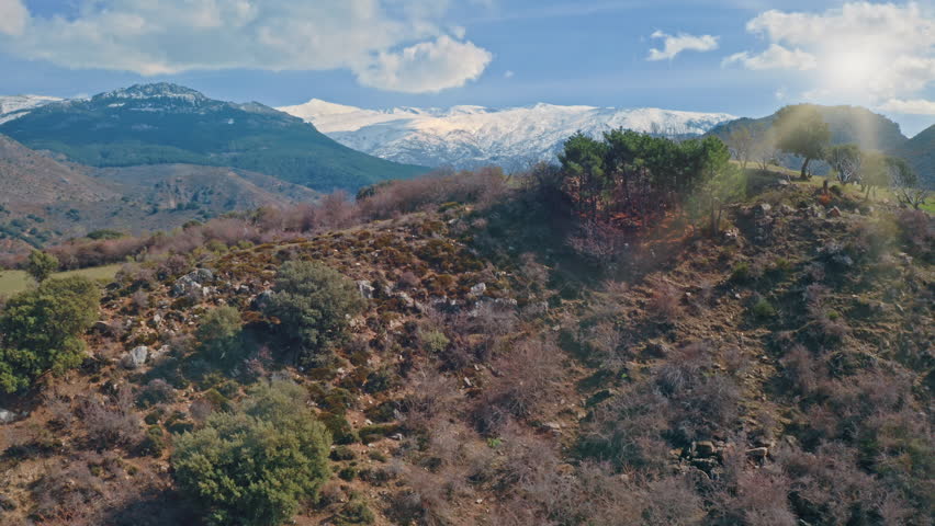 Snow on Sierra Nevada mountains hills in southern Spain illuminated by sunlight sun shining with rocky valleys green trees natural beauty adventure travel exploration historic Andalusian landscape