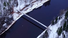 Suspension footbridge above dark river framed by snowy forest in Latvia - Powered by Shutterstock - Get 15% off with code: PIKWIZARD15
