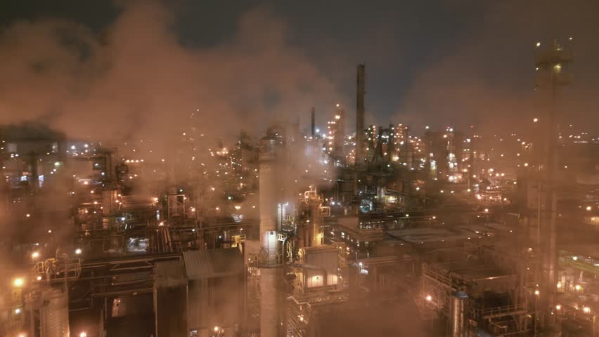 Night aerial shot of a refinery releasing heavy smoke from installations