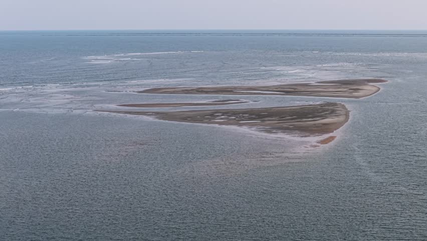 Aerial drone footage shows a small sandbar island in the Charleston waters surrounded by rippled blue water and open horizon.