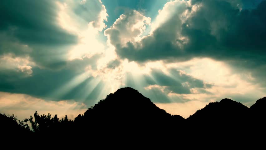 Time-lapse of mountain peaks in warm evening light with shifting shadows, glowing clouds, and rich golden hues.