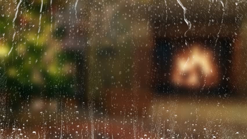 Raindrops on window with blurred Christmas interior and fireplace. Cozy holiday season atmosphere. Seamless loop