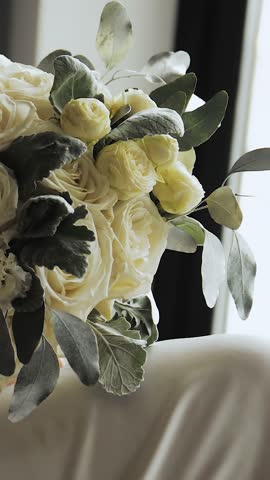 Vertical video. Bride holding a wedding bouquet of white roses, wedding morning, wedding preparations. Slow motion.