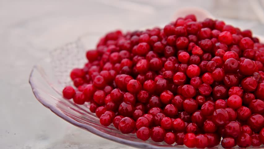 Marinated lingonberries on a clear glass plate sit on an ice-cold table. A Siberian appetizer to go with alcoholic drinks.