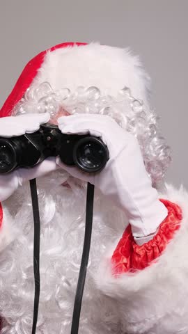 Santa claus looking through binoculars making a surprised face
