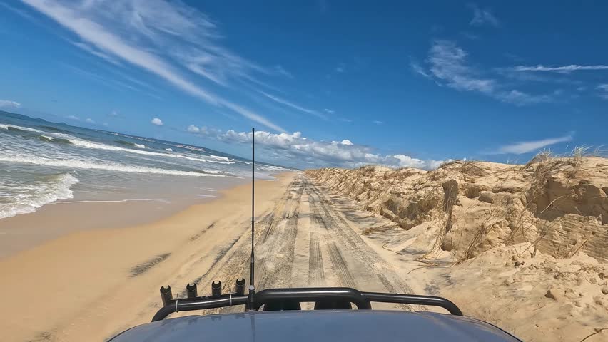 Point of view of a car driving at the beach of K´Gari between the ocean and a sandbank, Australia