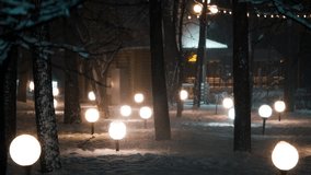Magical winter park with round street lamps lighting up a snowy path during a heavy blizzard at night. The beautiful scenery creates a cozy and peaceful atmosphere in the cold forest - Powered by Shutterstock - Get 15% off with code: PIKWIZARD15