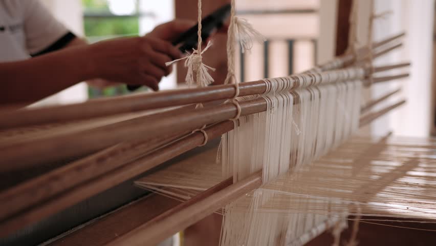 Woman weaving silk fabric on a traditional handloom using ancient weaving techniques, surrounded by nature, Cambodia, Siem Reap