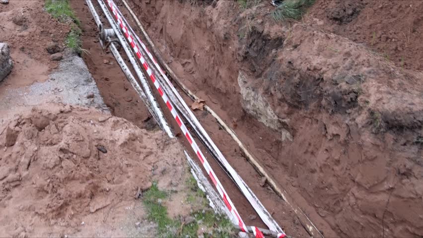 Laying electric cable in a deep trench with exposed underground utilities