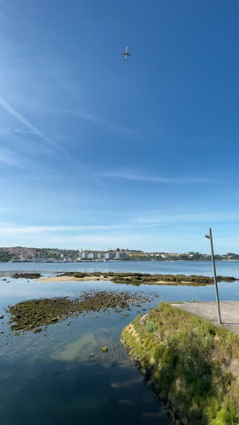 4K vertical wide angle video of passenger aircraft cruising in sky on bright sunny cloudless day. Transportation concept, ecology. Porto, Portugal