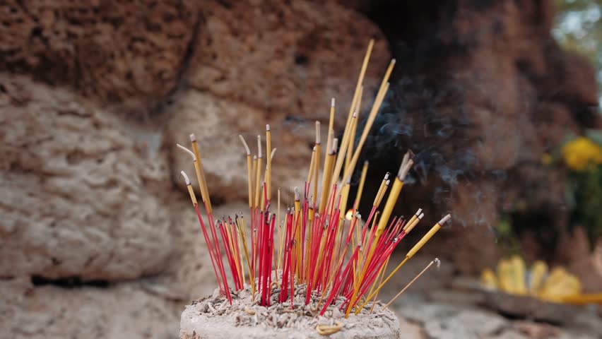 Colorful incense sticks burning in a pot at a traditional buddhist temple. The aromatic smoke rises during a worship ritual. Cambodia, Siem Reap