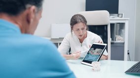 Professional female dentist in her modern office explaining a dental implant procedure to a male patient using a tablet with a 3d model - Powered by Shutterstock - Get 15% off with code: PIKWIZARD15