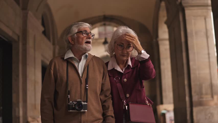 Happy retired elderly couple sightseeing and exploring an old city. The woman points at something interesting while the man looks on amazed